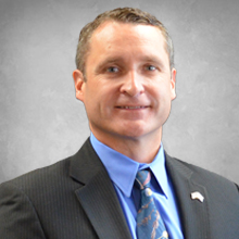 man wearing dark grey suite with blue shirt and tie headshot