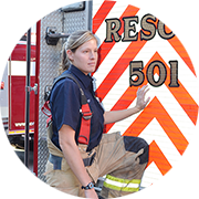female firefighter standing at the back of a firetruck with one leg on the firetrucks bumper