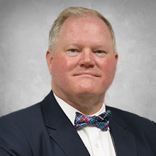 man wearing black suite with a white shirt and a red and blue bow tie